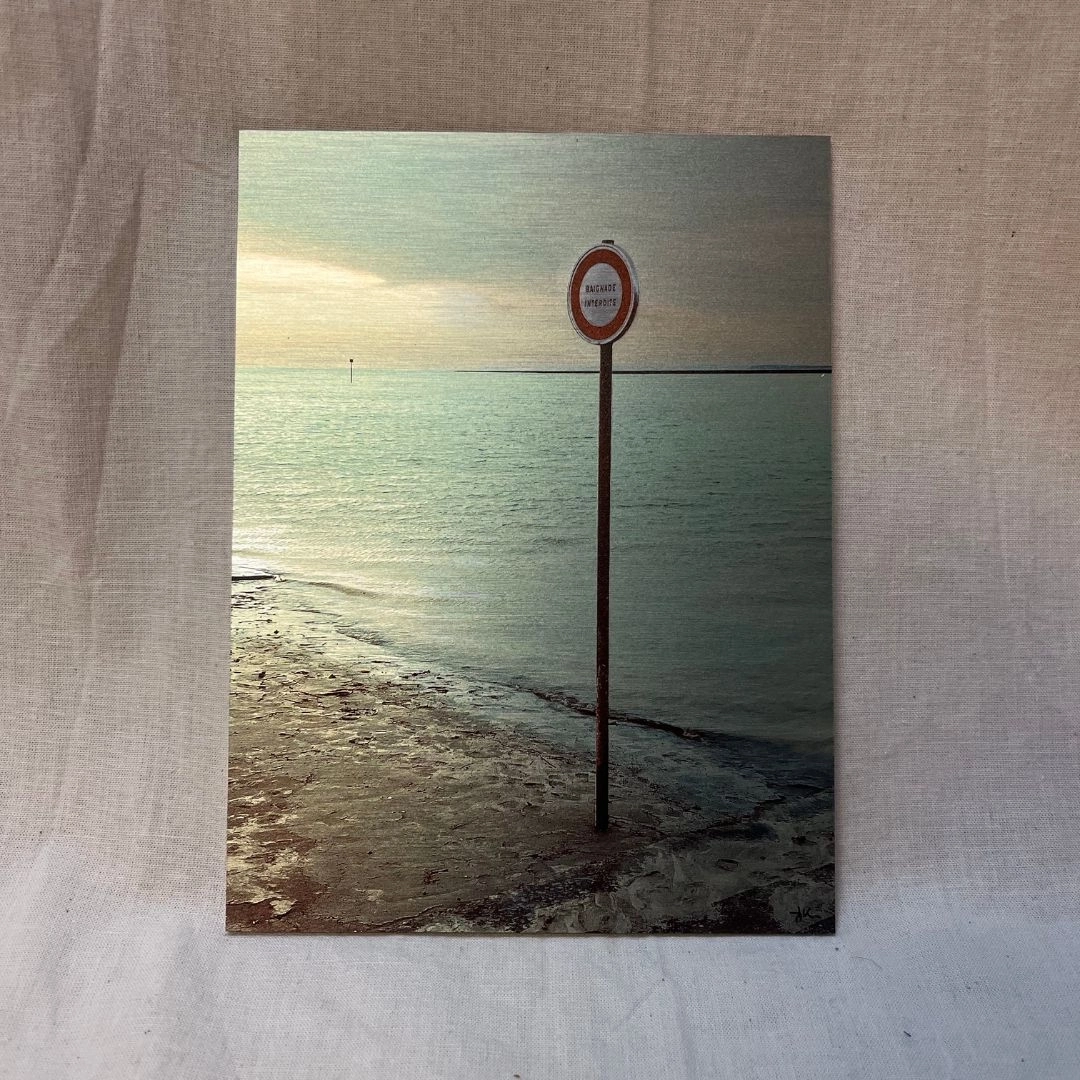 Beignade interdite (15x20) Prise à Saint-Valéry, avec une teinte bleue et un effet métallique, capturant la vague et un panneau « Baignade interdite » amusant.