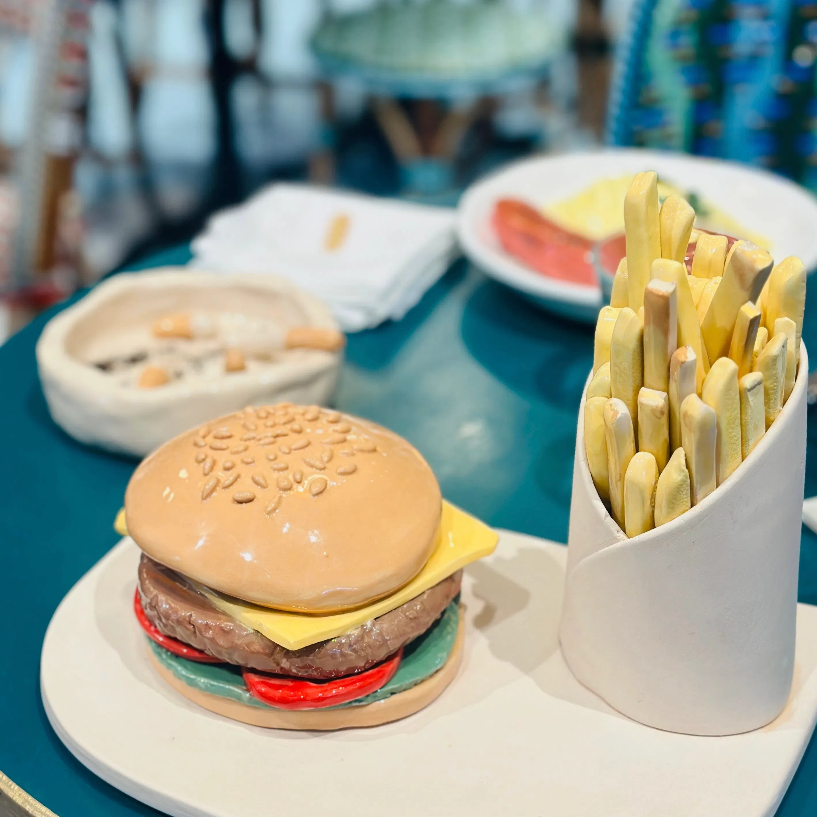 Assiette Burger Frites #2 en céramique. Fabriqué à la main à Paris. CAP Céramique Artisanale Parisienne. VENDUE au BON MARCHÉ, avec le COLLECTIF LES ÉTINCELLES, dans le cadre de l'exposition "PARIS PARIS" du 24 Septembre au 30 Octore 2024.