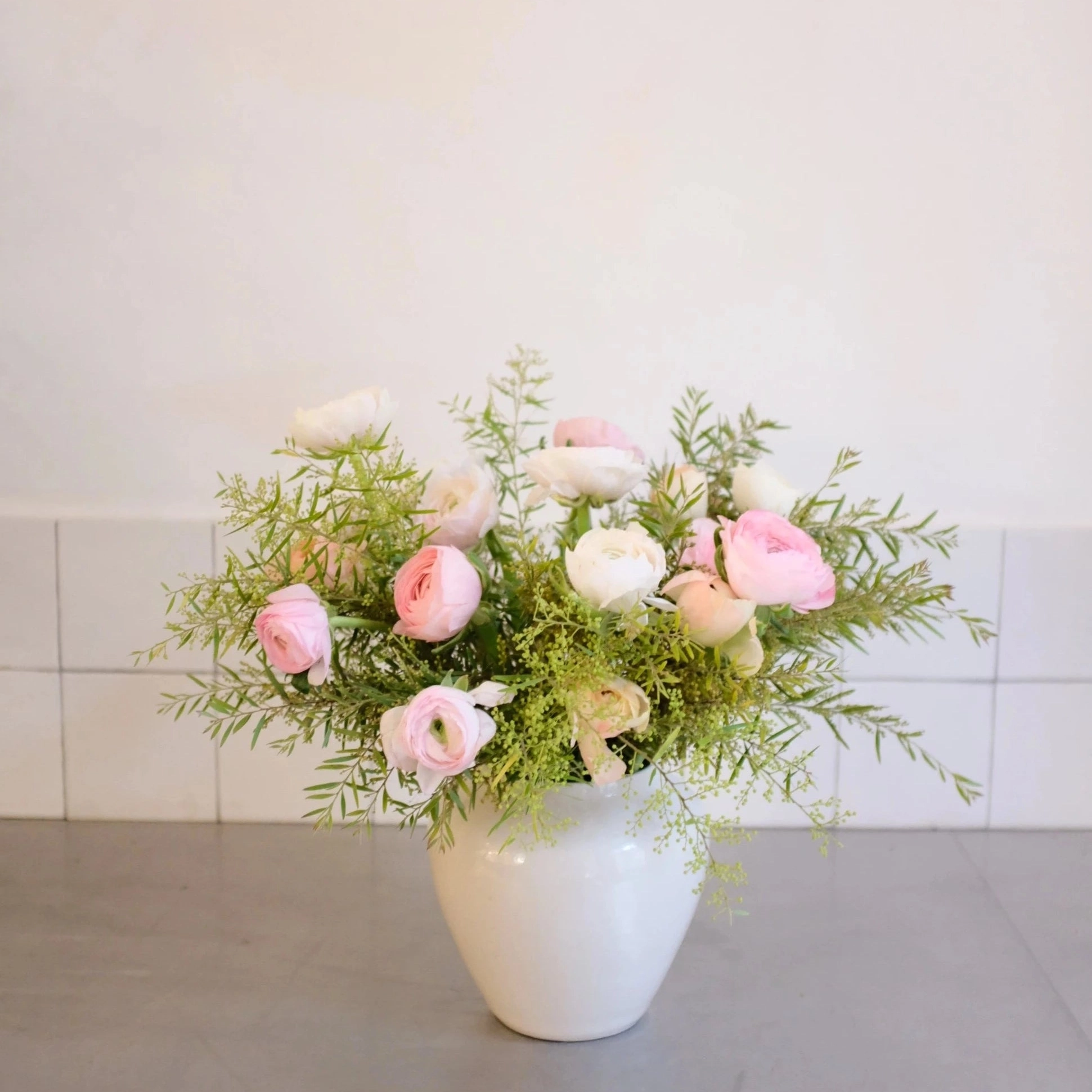 Découvrez notre sélection de vases en céramique fabriqués à la main au Portugal et spécialement conçus pour nos fleurs. D'OÙ VIENNENT NOS VASES? Nos vases sont tournés et émaillés à la main par une entreprise à taille humaine au Portugal . Ils ont été spécialement sélectionnés pour s'adapter aux tailles de nos bouquets et sont estampillés Désirée. DIMENSIONS ET COULEUR DU VASE La collection de vases portugais créée pour Désirée se compose de quatre tailles. Le vase rond mesure 18 cm de hauteur / 10 cm d'ouverture Conçu pour se marier avec tous les intérieurs, ce vase est de couleur blanche . L'émail lui apporte une touche de brillance . Pièces uniques, ces vases en céramique peuvent présenter de légères variations de couleur et de taille ainsi que des petites imperfections qui attestent de leur fabrication artisanale. Matière vivante, le grès ne doit pas être mis en contact direct avec les matières sensibles à l'humidité (bois par exemple). QUEL BOUQUET CHOISIR AVEC CE VASE? Si vous décidez d'offrir des fleurs avec le vase portugais rond , n ous vous conseillons de choisir un bouquet de taille " passionnément " (85€) ou " à la folie " (120€). Psst : le bouquet sur la photo est un bouquet des champs , couleur pastel, taille " passionnément ". Si vous hésitiez entre deux tailles de bouquet pour un vase portugais rond, nous vous conseillons de choisir la plus grande taille entre les deux. Ainsi, le bouquet aura plus d'allure et d'envergure ! LE PETIT PLUS? A chaque commande de bouquet et de vase, nous ajustons soigneusement les dimensions et la forme du bouquet afin qu'il s'adapte parfaitement au vase (sous réserve de choisir les tailles conseillées) .