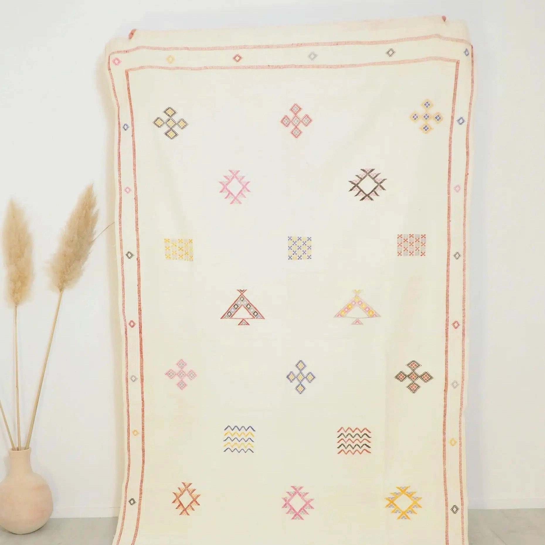 Tapis Sabra blanc en soie de cactus, une fibre naturelle extraite de l’aloé, qui lui confère beaucoup de douceur et de souplesse, tout en étant très robuste. C’est un tapis Marocain fait main, idéal pour l’été
Sa jolie couleur blanc cassé est obtenue grâce à une teinture végétale.
Son look épuré s’adaptera à tous les styles de décoration d’intérieurs: design minimaliste, bohème, ethnique, scandinave… Aussi bien dans une chambre que dans un salon. Détournez le en tenture murale, jeté de lit ou de canapé, tête de lit, etc…
Ses motifs berbères aux couleurs douces entièrement brodés à la main en font une pièce unique.
Les tisserandes se transmettent le savoir faire qui permet sa confection de génération en génération.
Il mesure 240 x 135 cm