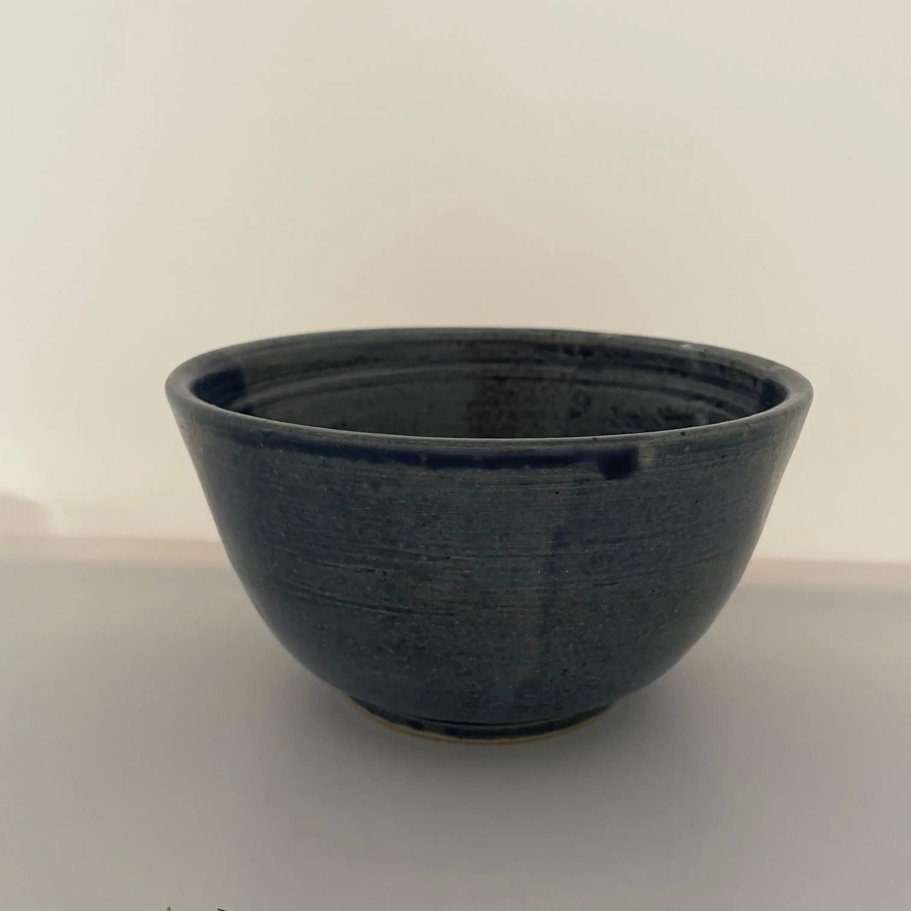 Un bol en céramique avec un émail bleu et un aspect texturé, idéal pour servir des soupes ou des entrées.