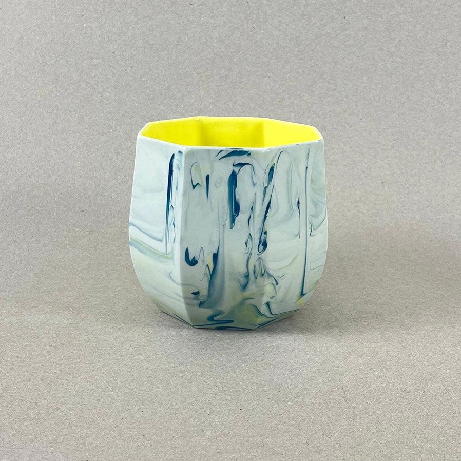 Porcelaine teintée dans la masse, couleurs bleu canard et jaune vif, intérieur jaune. Pièces à colorations variables. 12 x 12 x 11 cm. Ino, protectrice des marins et des naufragés, déesse des mers calmes. Une idée apaisante qu'il est rassurant d'avoir chez soi. Ce cache-pot aux allures de petit tonneau semble pouvoir résister aux tempêtes, et hébergera certainement nos plantes préférées, celles qu'on emmènera en toutes circonstances. Les pièces sont obtenues par coulage, une à une, à la main. Le précipité de couleur rend chaque pièce unique.