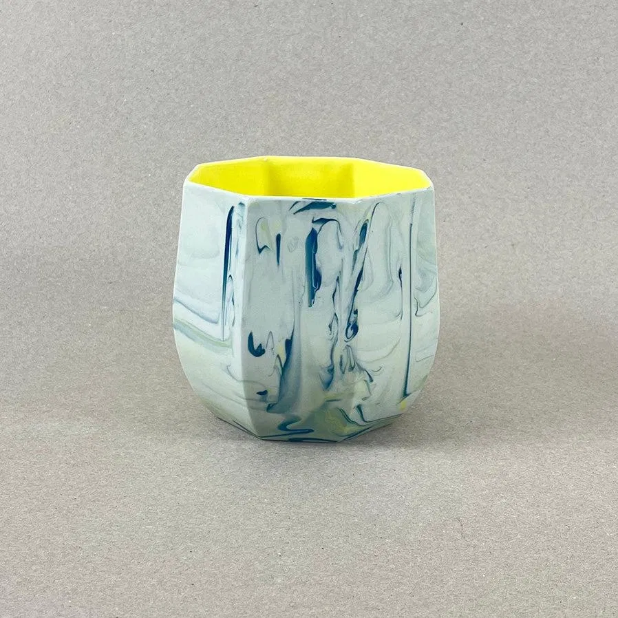 Porcelaine teintée dans la masse, couleurs bleu canard et jaune vif, intérieur jaune. Pièces à colorations variables. 12 x 12 x 11 cm. Ino, protectrice des marins et des naufragés, déesse des mers calmes. Une idée apaisante qu'il est rassurant d'avoir chez soi. Ce cache-pot aux allures de petit tonneau semble pouvoir résister aux tempêtes, et hébergera certainement nos plantes préférées, celles qu'on emmènera en toutes circonstances. Les pièces sont obtenues par coulage, une à une, à la main. Le précipité de couleur rend chaque pièce unique.