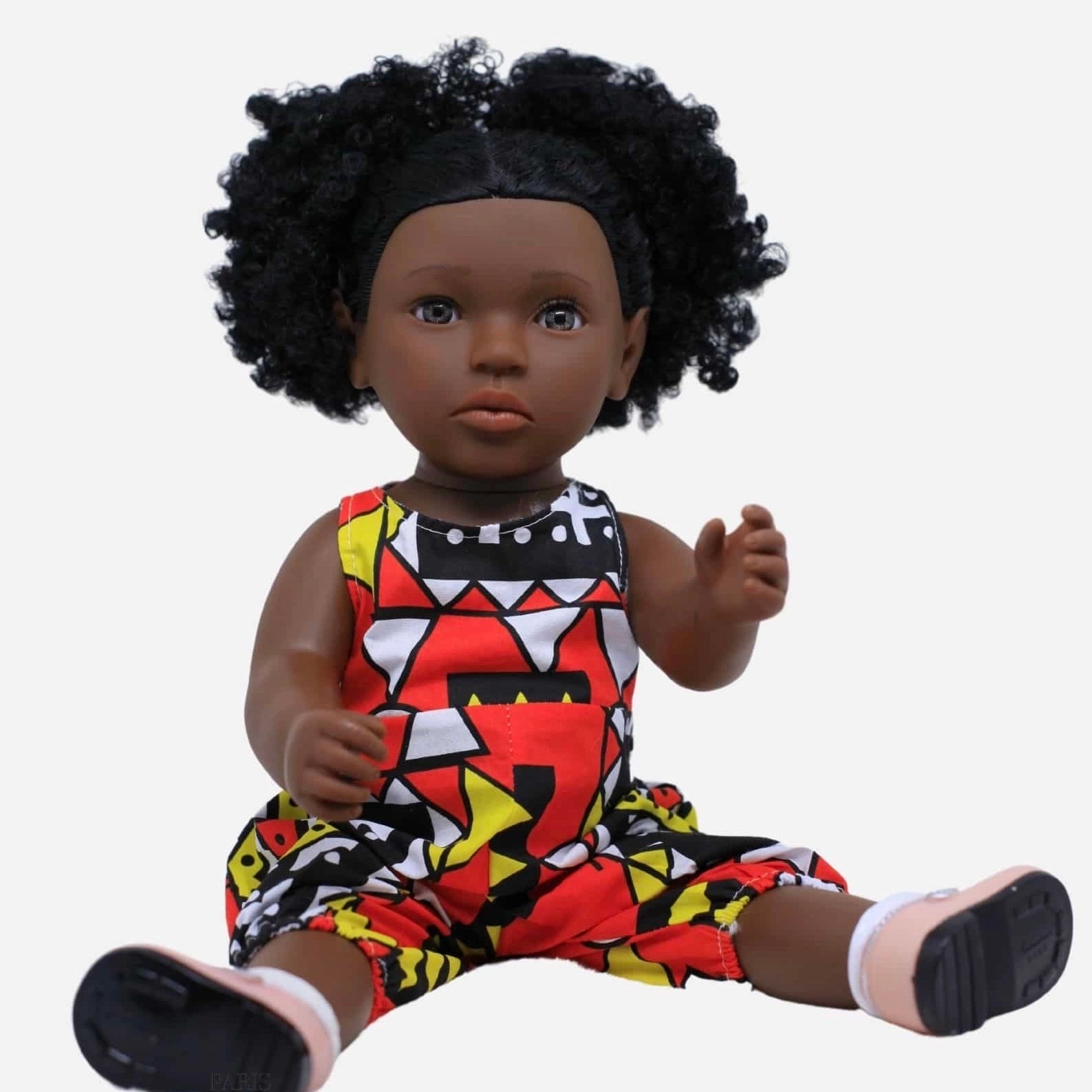 Poupée noire « Linguère Dégueune Mbaye » a des cheveux noirs bouclés. Cette poupée représente l’identité d’une petite fille métisse. Elle porte une combinaison en Wax dont la couleur dominante est le rose