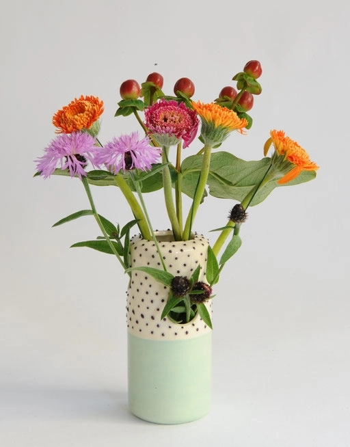 Ce vase en céramique allie élégance et fantaisie avec sa base d'un vert pastel doux et son col orné de petits pois noirs sur fond blanc. Sa forme élancée met en valeur tous types de bouquets, des plus champêtres aux plus sophistiqués.