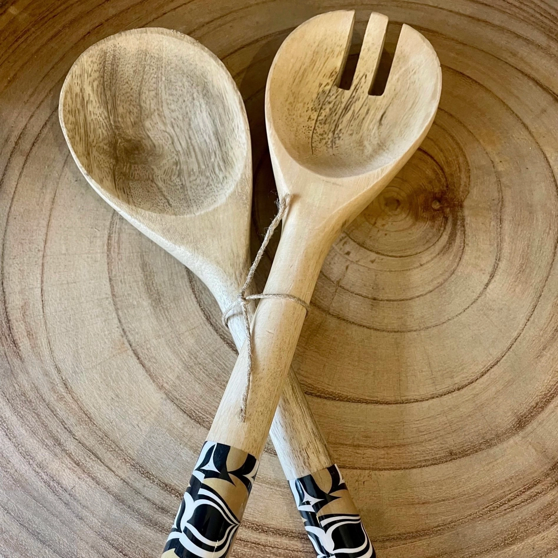 La paire de couverts est constituée d’une fourchette et d’une cuillère, en bois de manguier, avec le manche en résine, aux motifs noirs et blancs avec fond beige.