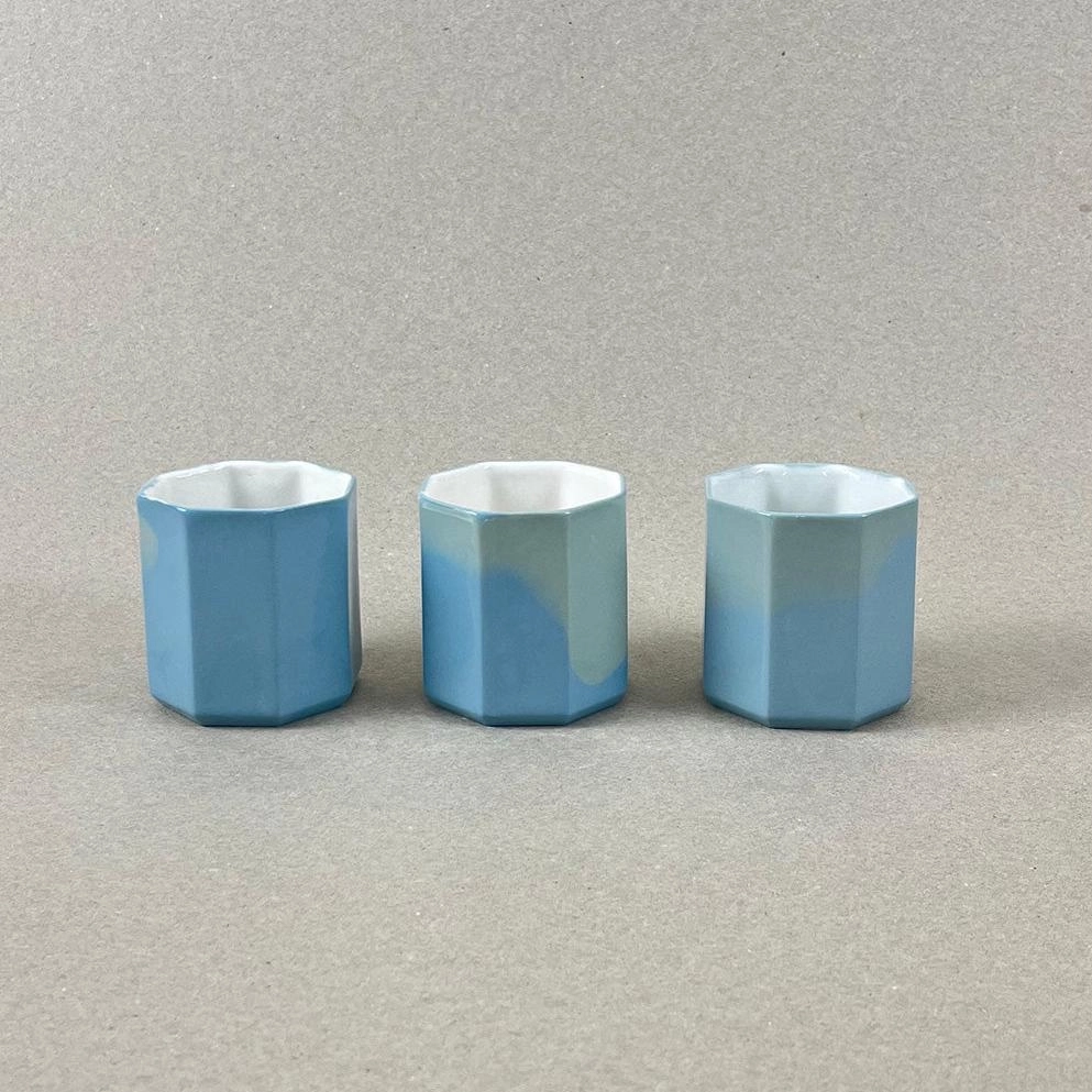 Porcelaine teintée dans la masse. Pièces à colorations variables. 6 x 6 x 6 cm. La part du voyageur invite à servir un café supplémentaire, destiné à une personne de passage. Et puisque son motif s'y prête, en attendant le voyageur, laissons nous rêver à reconnaître des formes dans les nuages. Nos objets sont obtenus par coulage, un à un, à la main. Ils présentent chacun des particularités qui attestent de leur aspect artisanal. Nous proposons des pièces à caractère unique, ou en petite série.