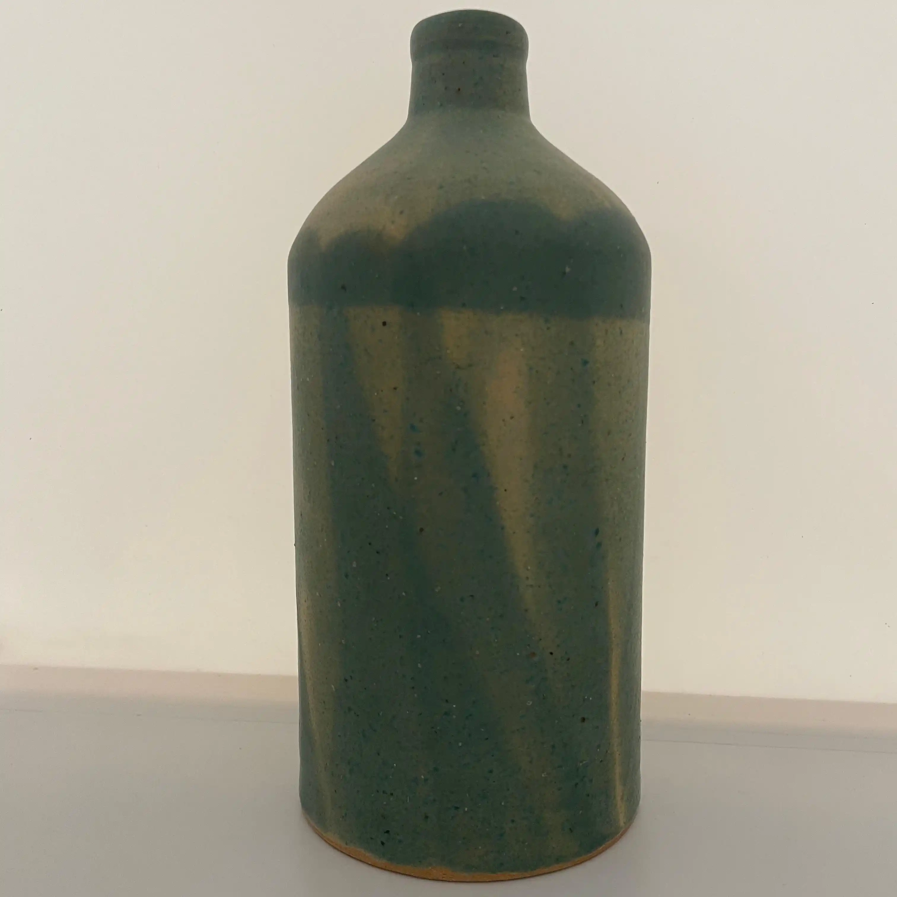 Une bouteille pouvant servir comme vase pour des fleurs, réalisée avec un émail issu d'une recherche à base de cendres de bois de l'Oise, coloré en vert.