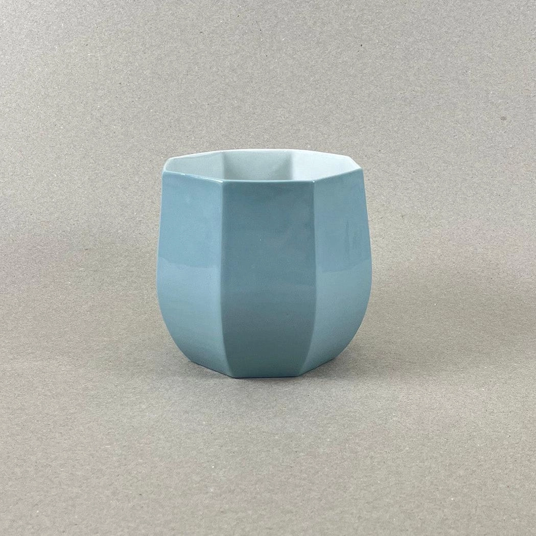 Porcelaine teintée dans la masse, couleurs bleu canard et jaune vif, intérieur jaune. Pièces à colorations variables. 12 x 12 x 11 cm. Ino, protectrice des marins et des naufragés, déesse des mers calmes. Une idée apaisante qu'il est rassurant d'avoir chez soi. Ce cache-pot aux allures de petit tonneau semble pouvoir résister aux tempêtes, et hébergera certainement nos plantes préférées, celles qu'on emmènera en toutes circonstances. Les pièces sont obtenues par coulage, une à une, à la main. Le précipité de couleur rend chaque pièce unique.