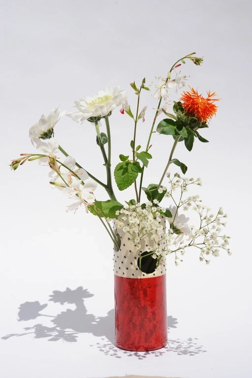 Ce vase en céramique allie élégance et fantaisie avec sa base d'un vert pastel doux et son col orné de petits pois noirs sur fond blanc. Sa forme élancée met en valeur tous types de bouquets, des plus champêtres aux plus sophistiqués.