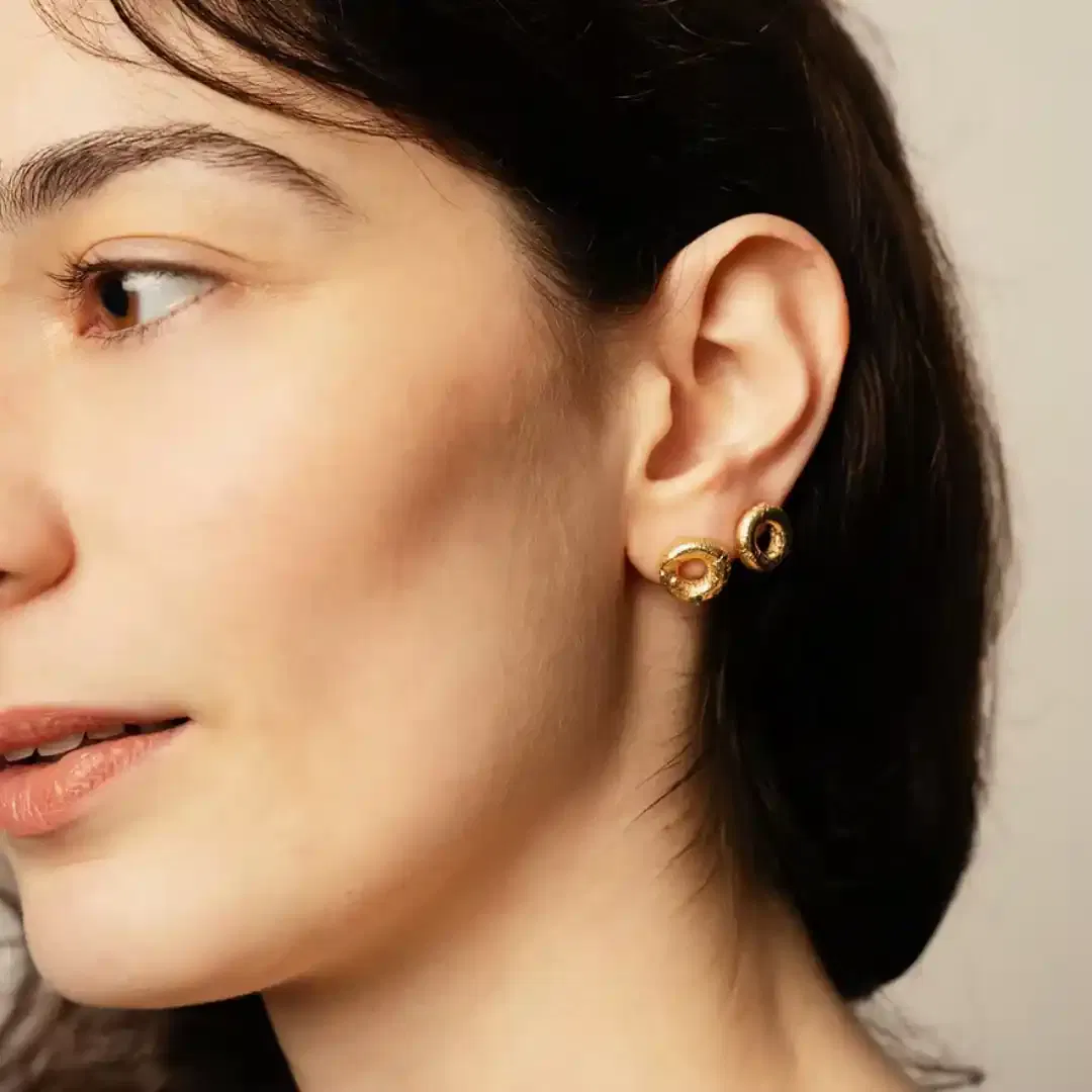 Les puces NUBIA sont deux cercles épais qui viennent se poser sur le lobe. Leur texture unique et irrégulière en font tout leur charme. Ce bijou a été fabriqué à partir de perles de métal africaines, dont la texture varie d'une pièce à l'autre. Légèrement asymétrique, vous trouverez d'un côté une petite pierre.
Les bijoux Atelier Nicol sont entièrement fabriqués en laiton (sans nickel, non allergène), puis recouverts d'un bain d'or. Le placage trois microns permet à chaque pièce de pouvoir vous accompagner au quotidien et de durer dans le temps. Les bijoux plaqué argent sont, quant à eux, recouvert d'un bain d'argent de dix microns.