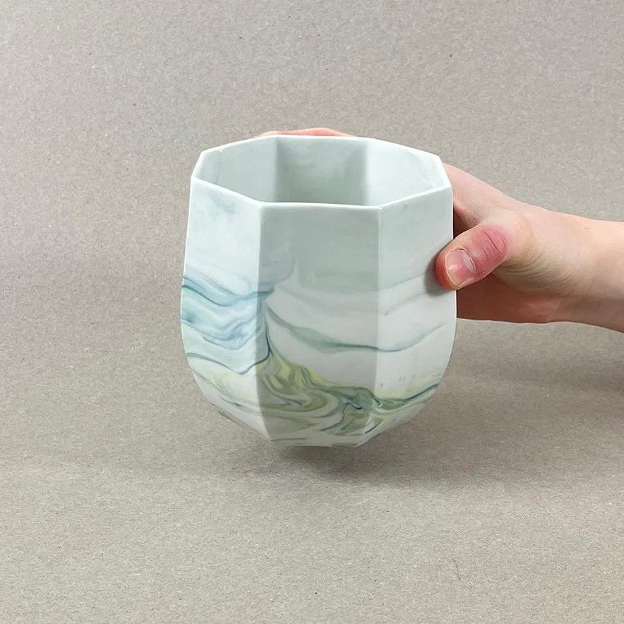 Porcelaine teintée dans la masse, couleurs bleu canard et jaune vif. Pièces à colorations variables. 12 x 12 x 11 cm. Ino, protectrice des marins et des naufragés, déesse des mers calmes. Une idée apaisante qu'il est rassurant d'avoir chez soi. Ce cache-pot aux allures de petit tonneau semble pouvoir résister aux tempêtes, et hébergera certainement nos plantes préférées, celles qu'on emmènera en toutes circonstances. Les pièces sont obtenues par coulage, une à une, à la main. Le précipité de couleur rend chaque pièce unique.