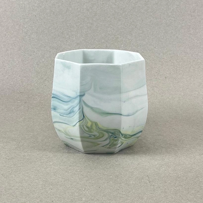 Porcelaine teintée dans la masse, couleurs bleu canard et jaune vif. Pièces à colorations variables. 12 x 12 x 11 cm. Ino, protectrice des marins et des naufragés, déesse des mers calmes. Une idée apaisante qu'il est rassurant d'avoir chez soi. Ce cache-pot aux allures de petit tonneau semble pouvoir résister aux tempêtes, et hébergera certainement nos plantes préférées, celles qu'on emmènera en toutes circonstances. Les pièces sont obtenues par coulage, une à une, à la main. Le précipité de couleur rend chaque pièce unique.