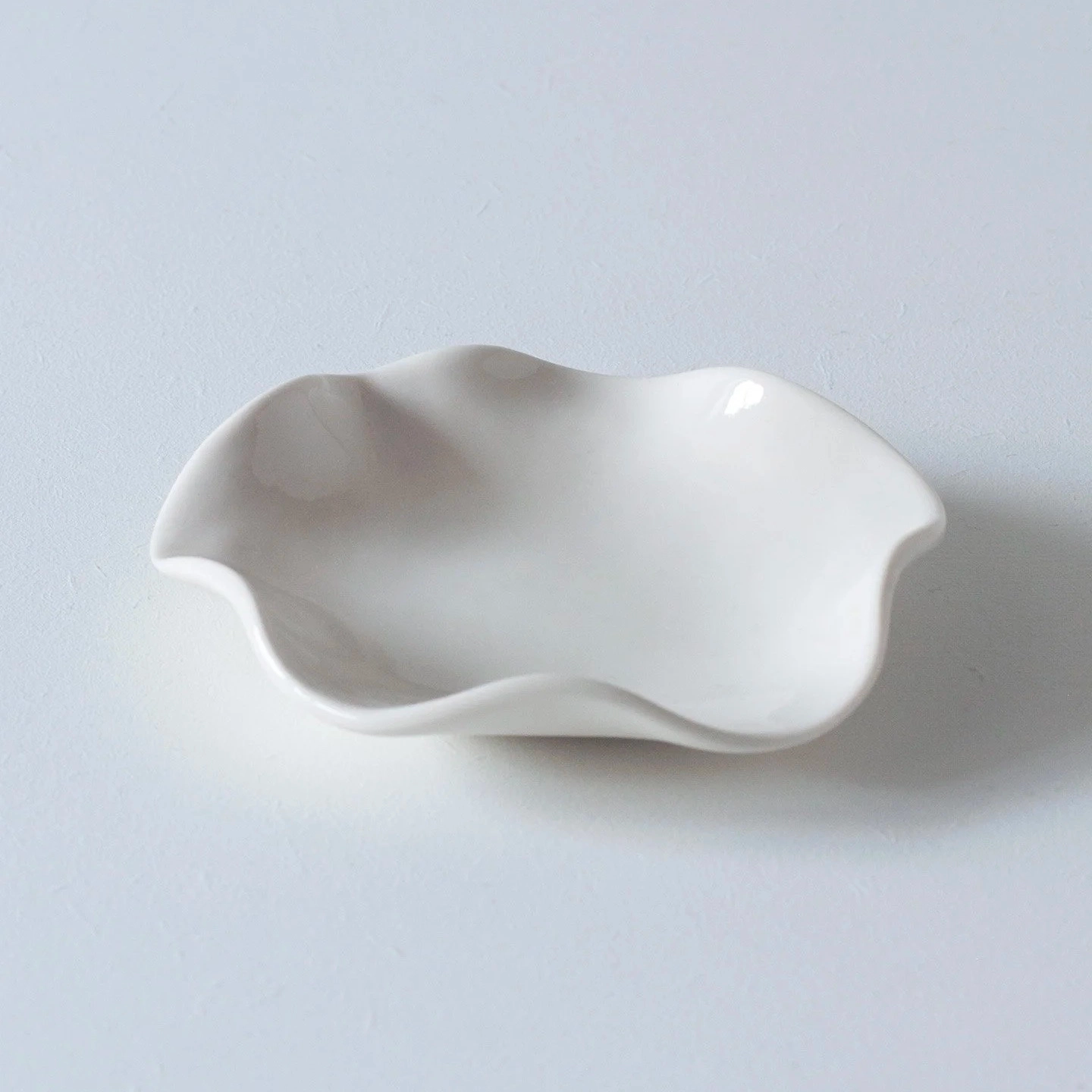 Coupelle en porcelaine blanche rêvée pour accueillir de précieux petits bijoux la nuit ou des fantaisies le jour.
Diamètre : 10 cm. Intérieur émail brillant. Extérieur mat. Forme aléatoire