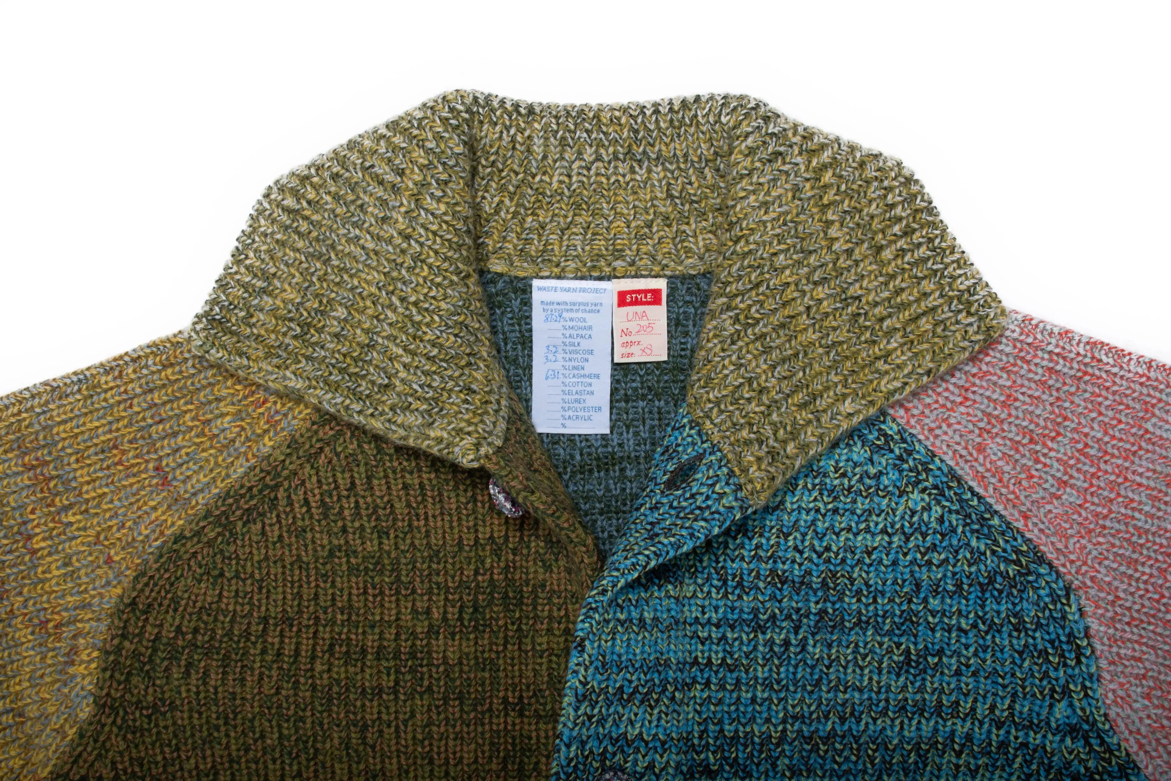 Veste/cardigan tricoté taille XS. UNA est un parfait mélange entre une veste et un cardigan, avec un col et des poignets boutonnés.
Elle présente des fentes sur les coutures latérales pour une coupe droite et structurée. Les boutons sont fabriqués à partir de plastique recyclé.
La couleur et le fil sont choisis par la roue de la fortune WYP, ce qui rend chaque pièce véritablement unique au monde.