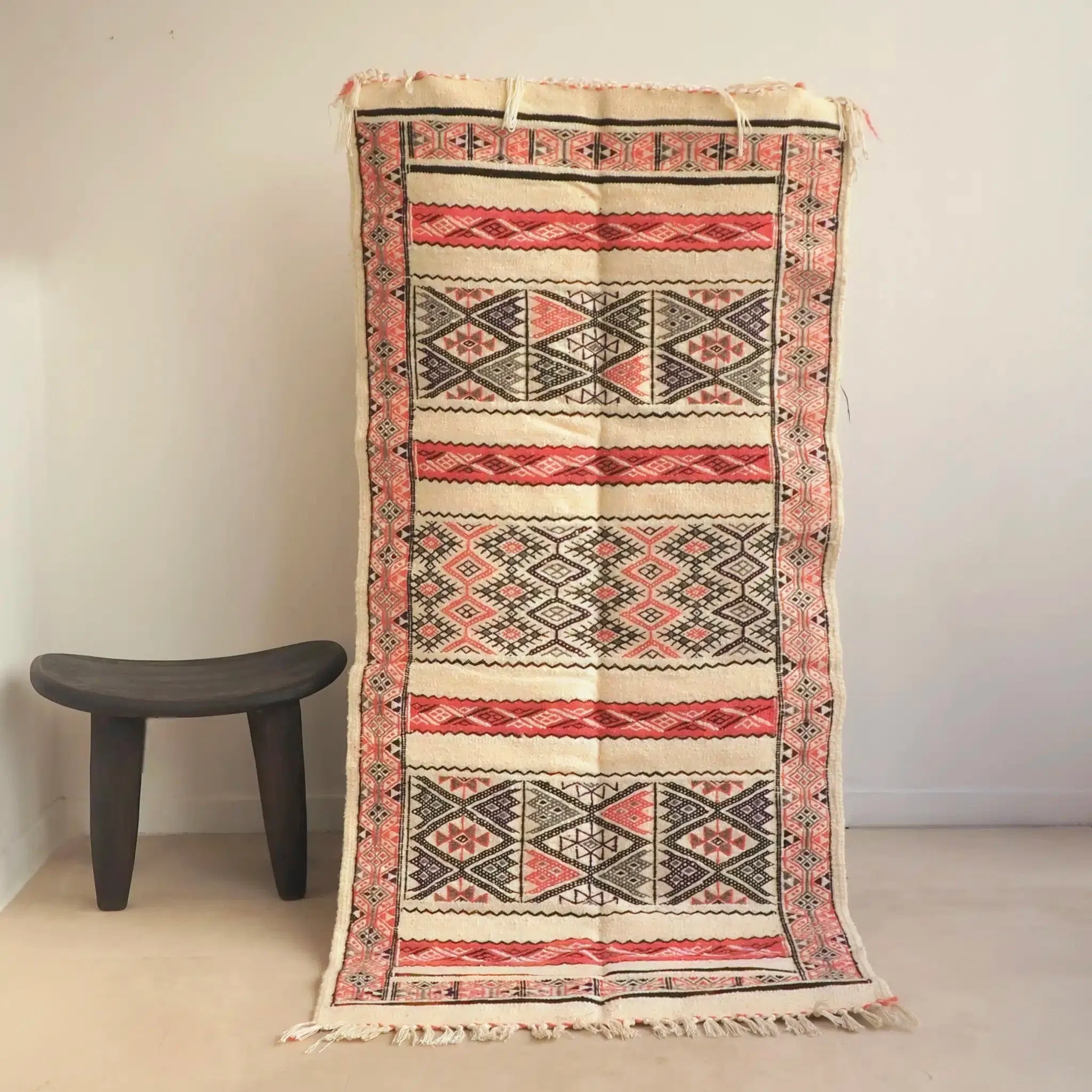 Tapis kilim Amazigh d’Algérie blanc et rose, tissé à la main à Beni Isguen, au cœur de la région de Ghardaïa, qui reflète l’héritage culturel de la vallée du M’zab. Réalisé en pure laine de haute qualité, il perpétue les savoir-faire ancestraux des artisanes mozabites, transmis de génération en génération.
Ce tapis se distingue par ses motifs géométriques Ben Isguen, à l’esthétique raffinée et minimaliste. Il sera parfait dans un salon lumineux ou en tête de lit dans une chambre.
Dimensions : 160 x 75 cm environ