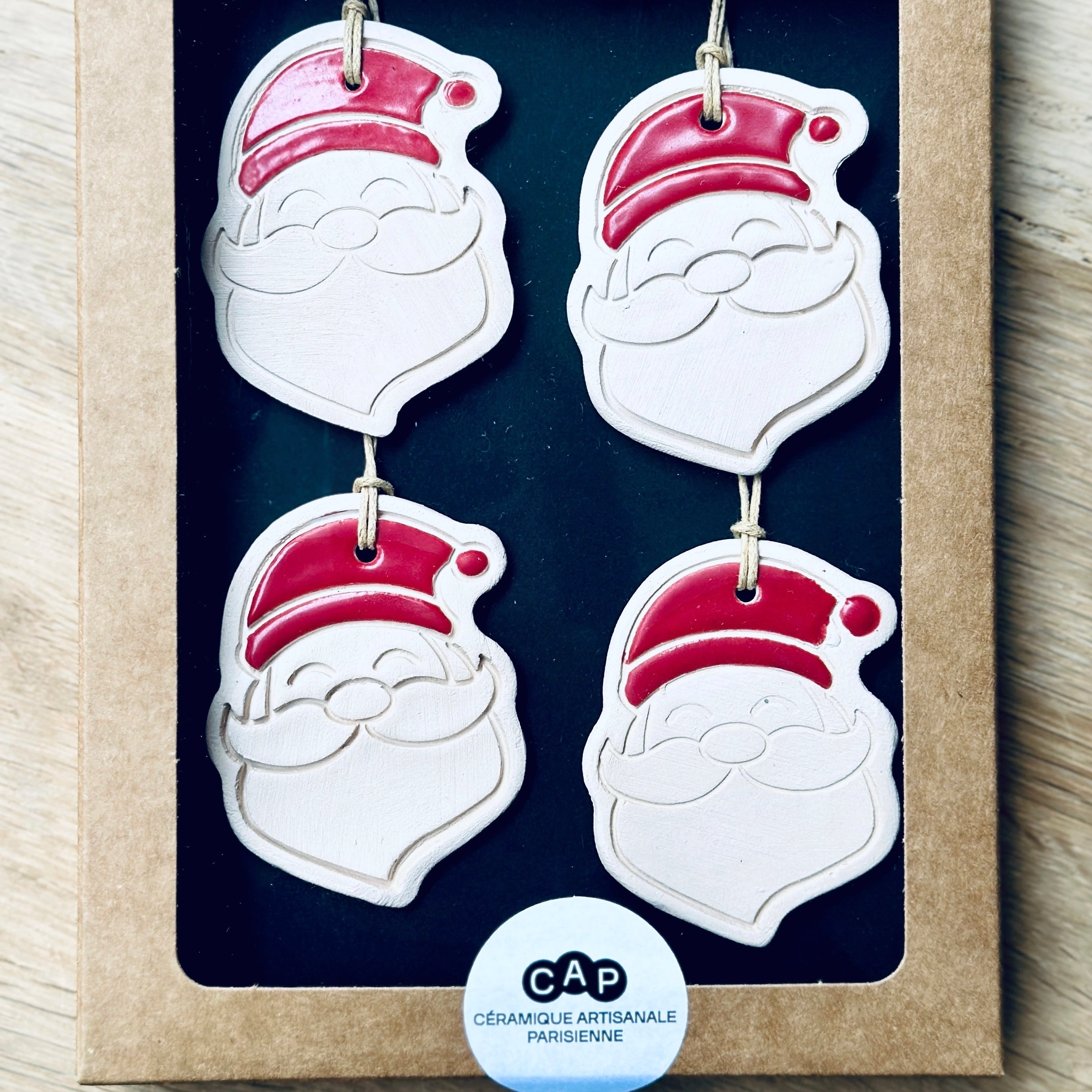 4 Pendentifs père Noël pour sapin de Noël. Fabriqués à la main en faïence, à Paris. Environ 5x4,5 cm. Ficelle résistante en coton ciré. CAP Céramique Artisanale Parisienne
