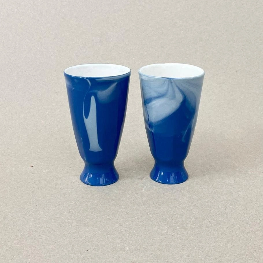 Porcelaine teintée dans la masse Pièces à colorations variables. Prix à la pièce h: 10,5cm, diam. 6 cm Contenance : 180 ml Se lever et débuter un moment qui ne devrait jamais se finir. Comme boire un café en regardant le soleil se lever sur la montagne et en écoutant une douce musique pour accompagner cette contemplation. Ce mazagran aux couleurs de l'aube sur les massifs montagneux offre quelques minutes de repos avant d'entamer la journée. Les objets de cette collection sont obtenues par coulage, un à un, à la main. L'aspect marbré qui se dessine délicatement à la surface provient de l'ajout d'une couleur directement dans la pâte de porcelaine au moment du coulage.