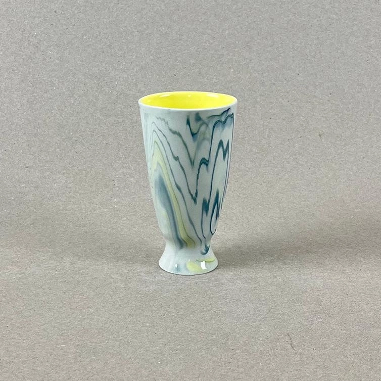 Porcelaine teintée dans la masse Pièces à colorations variables. h: 10,5cm, diam. 6 cm Contenance : 180 ml Se lever et débuter un moment qui ne devrait jamais se finir. Comme boire un café en regardant le soleil se lever sur la montagne et en écoutant une douce musique pour accompagner cette contemplation. Ce mazagran aux couleurs de l'aube sur les massifs montagneux offre quelques minutes de repos avant d'entamer la journée. Les objets de cette collection sont obtenues par coulage, un à un, à la main. L'aspect marbré qui se dessine délicatement à la surface provient de l'ajout d'une couleur directement dans la pâte de porcelaine au moment du coulage.