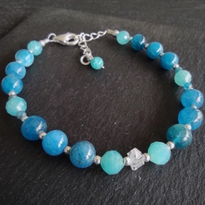 Bracelet composé de apatites bleues et d’un cristal biterminé. Réglable grâce à la chaînette en argent.