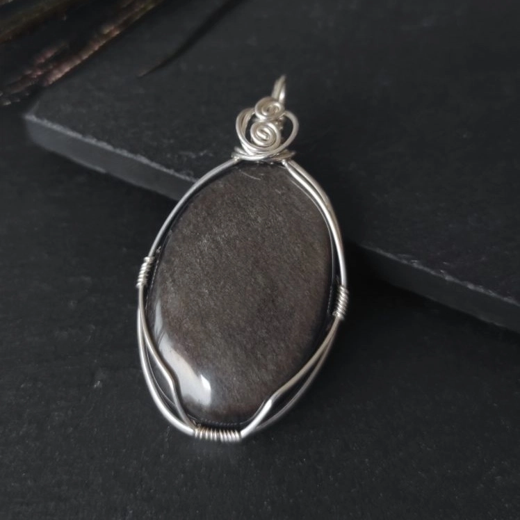 Pendentif composé d’une grande obsidienne argentée, montage sur fil d’argent 925 poinçonné. Pierre naturelle.