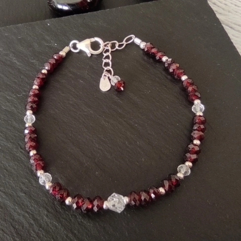 Bracelet composé de grenats rouges facettés, de perles de cristal de roche facettées, et d’un cristal biterminé. Chaînette en argent